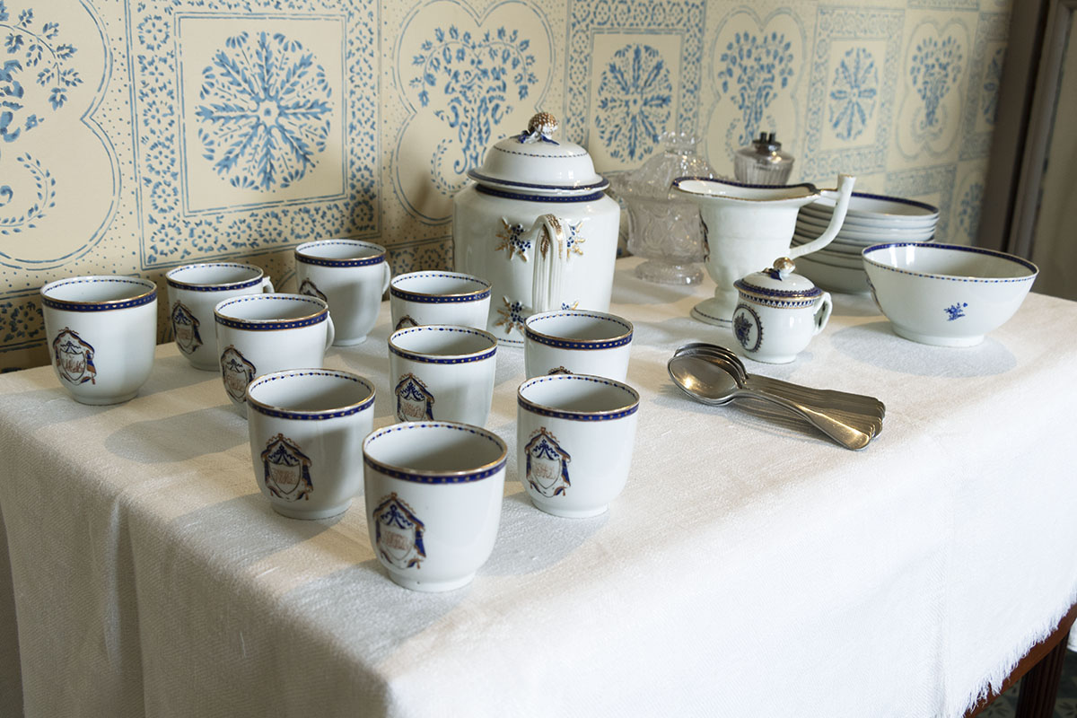 Noah Webster Home / china Table containing white dishes with blue pattern; wallpapered wall in background
