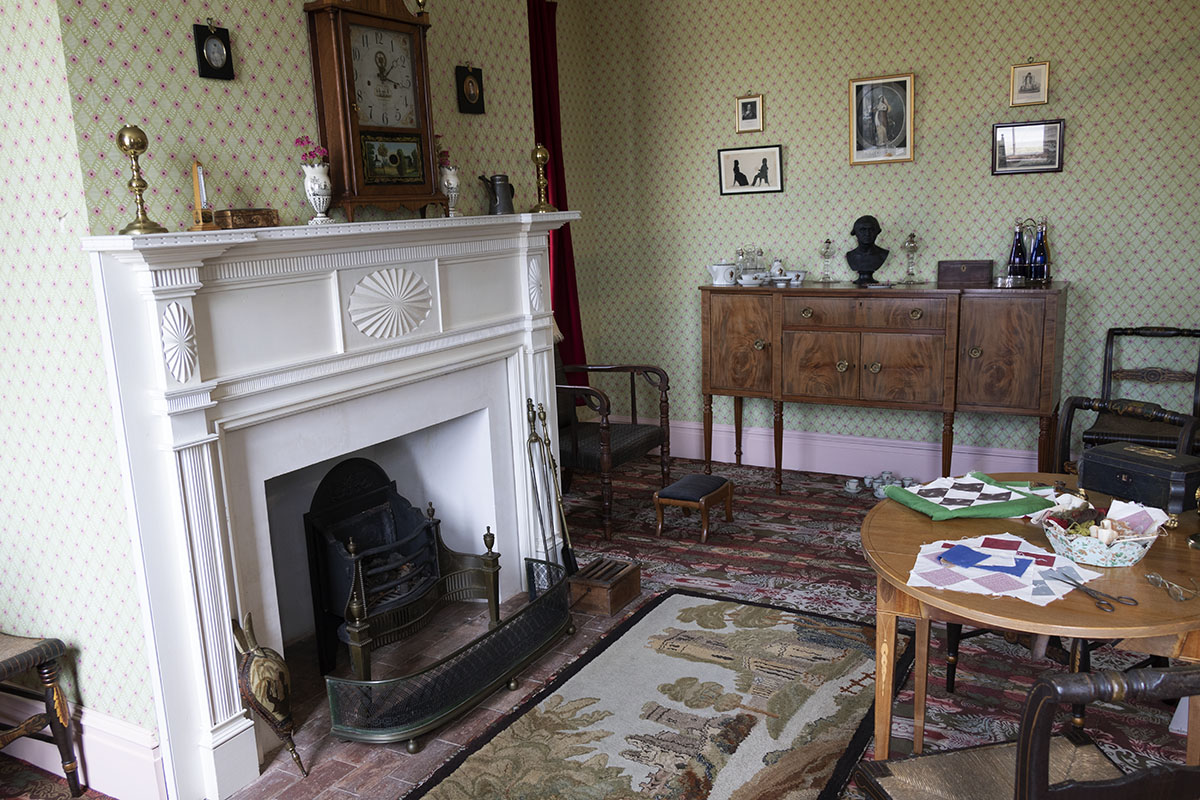 Noah Webster Home / sitting room Part of carpeted and wallpapered room showing fireplace, sideboard, table and chairs