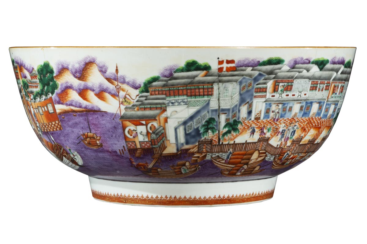 Short-ish bowl with wide base and even wider sides, decorated with a wharfside scene of a harbor, mountains, buildings, people, docks, boats, and water