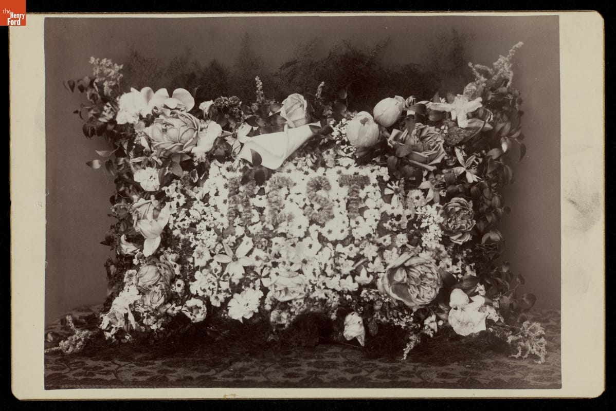Black-and-white image of pillow-shaped arrangement of flowers and greenery