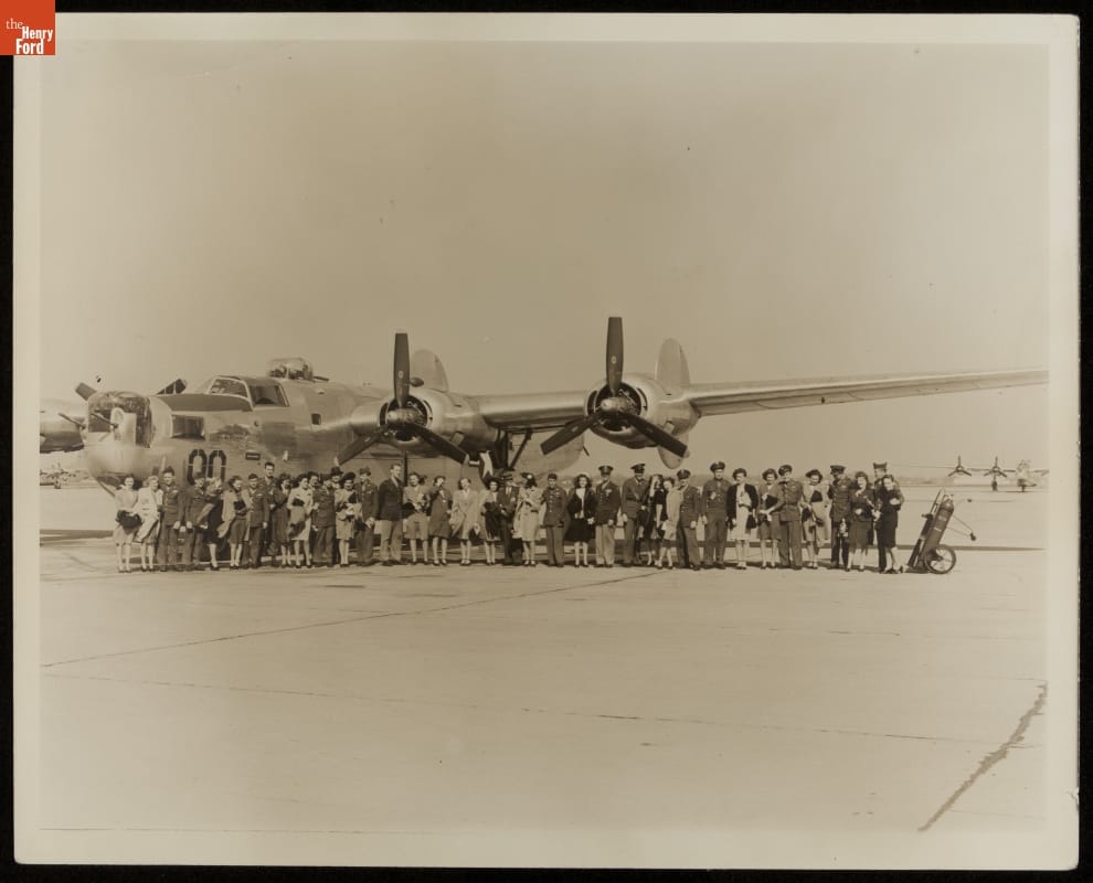 AFL-USO Program at Willow Run Bomber Plant, April 1945 Large group of men and women pose in front of airplane on tarmac