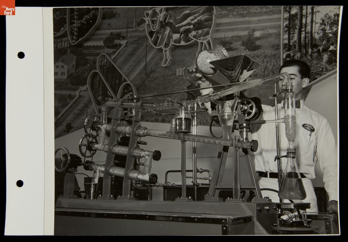 Soybean Processing for Fiber and Oil, Ford Exposition, New York World's Fair, 1939 Man pours beans into an apparatus in front of an agricultural mural