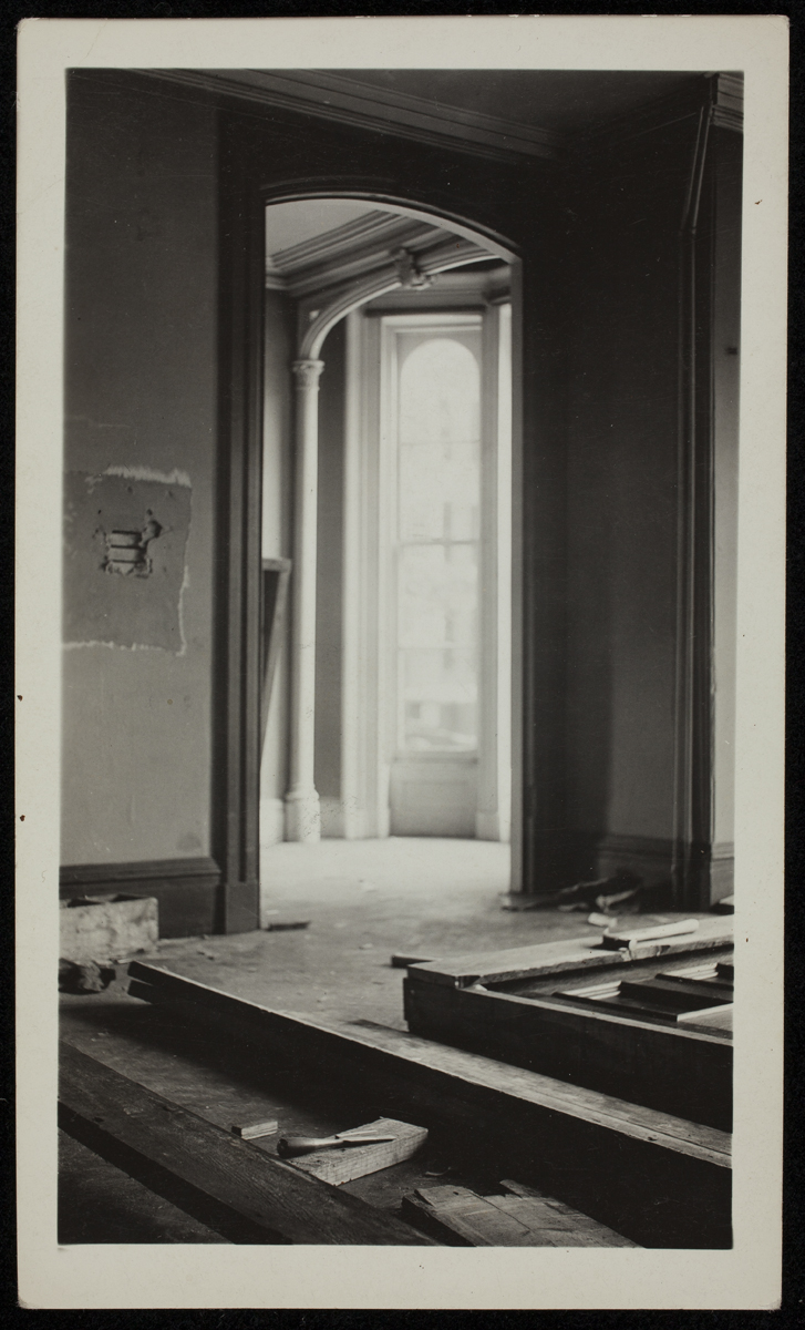 Interior of room looking toward a foyer with windows or door