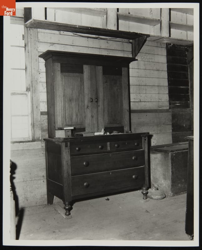 Black-and-white photo of dresser and hutch among other furniture