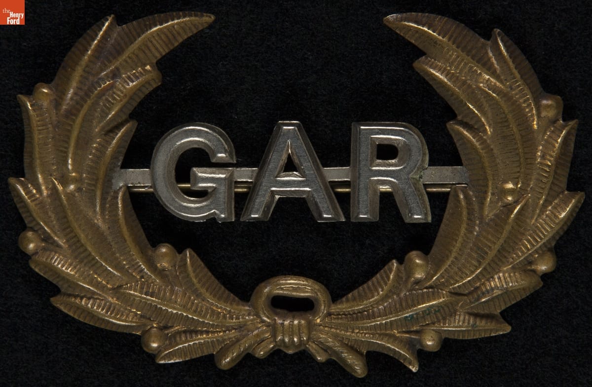 Metal pin with gold laurel and silver letters 
