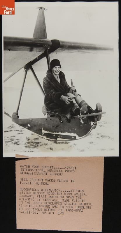 Amelia Earhart in an Experimental Ice-Glider at Wildwood Farm, Lake Orion, Michigan, March 1929 Woman sits on a thin conveyance on snow with wings extending on either side above her; typewritten text underneath photo