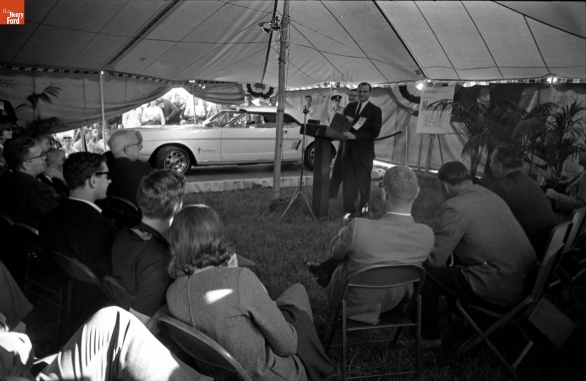 Lee Iacocca introducing the Mustang II concept car at Watkins Glen in October 1963 in a tent.