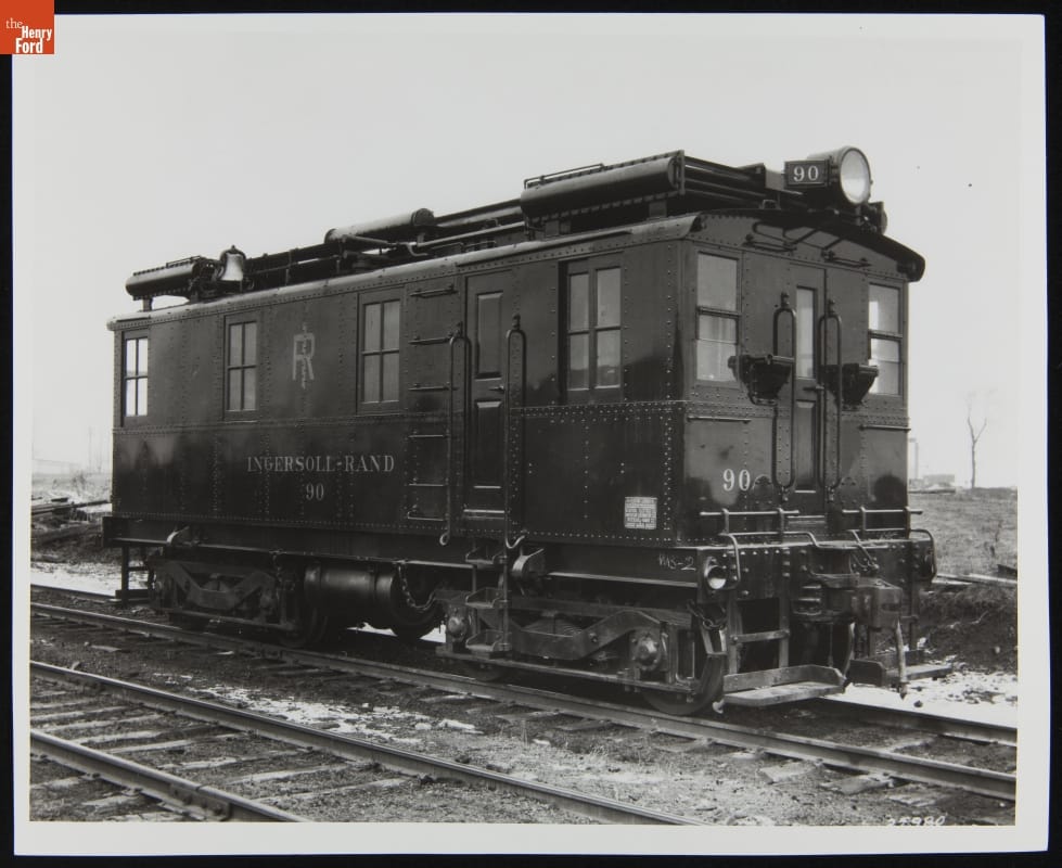 Black-and-white photo of a boxy railcar on railroad tracks