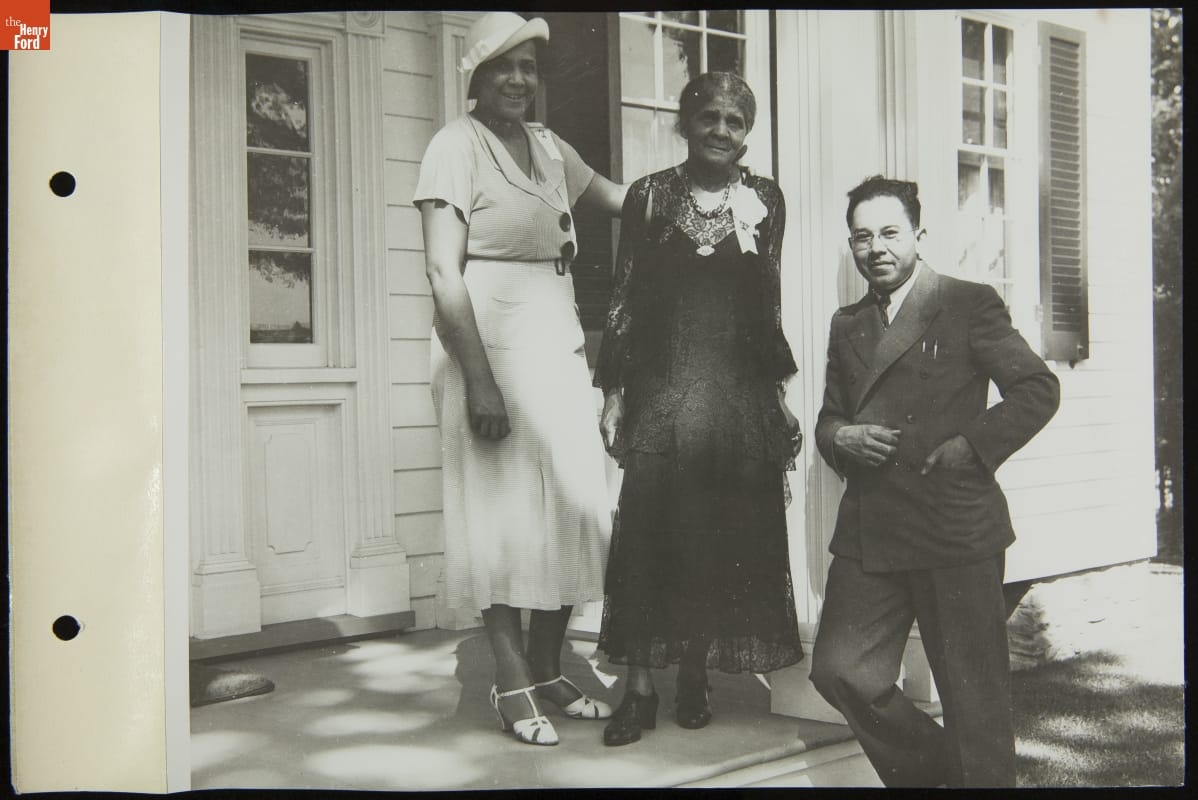 Lilybel Foster, Georgia Singleton Ralls, and Paul Foster at Stephen Foster Home Dedication, Greenfield Village, July 4, 1935 Two women and one man pose for a photo on the porch or front steps of a house