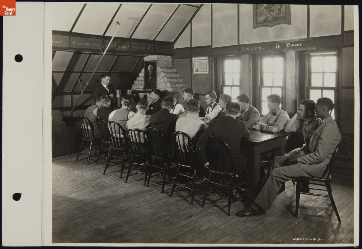 Claude Harvard with Other Radio Club Members and Teacher, Henry Ford Trade School, March 1930 Young men sit around a long table looking at a man standing at one end