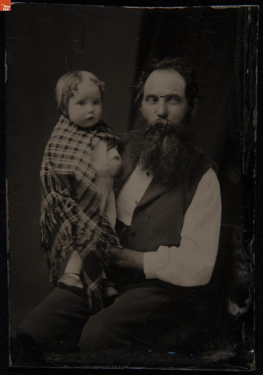 Man holding child wrapped in plaid shawl or blanket