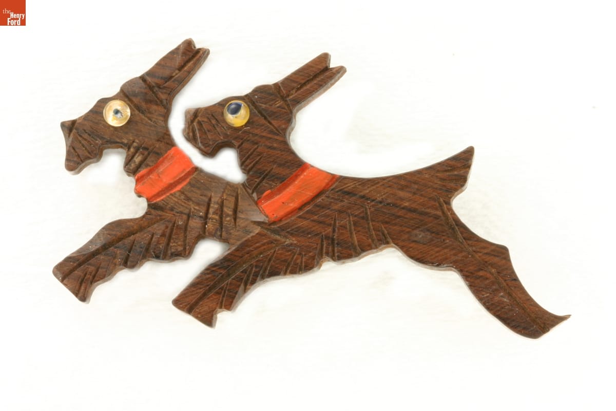 Brown wooden pin carved to depict two Scottie dogs wearing red collars running