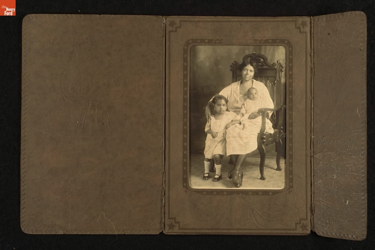 Seated Woman with Two Children, circa 1920 Black woman, seated, with infant on lap and toddler standing beside her