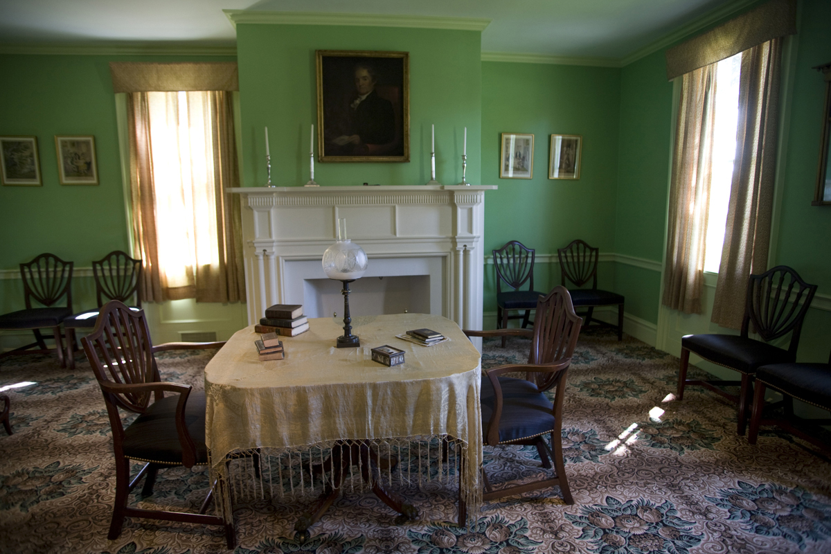Noah Webster Home in Greenfield Village, September 2007 / Photographed by Michelle Andonian Room with patterned carpet, green walls, table and chairs in middle of room and additional chairs around the perimeter