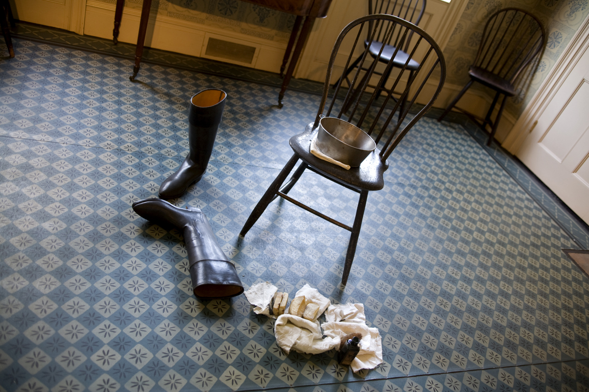 Noah Webster Home in Greenfield Village, September 2007 Pair of boots lying on patterned blue floor next to chair with tub; rags nearby