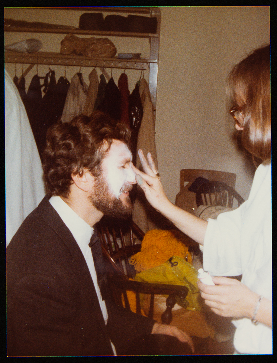 Curt Braden, 1981, having Halloween makeup applied Seated man having makeup applied by a standing woman