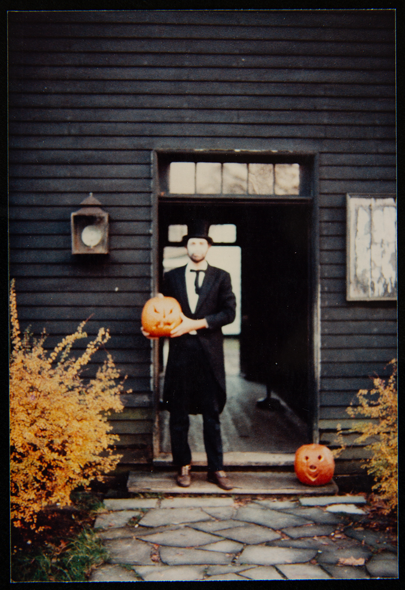 Curt Braden at the Lincoln County Courthouse with jack-o-lanterns Man in long jacket and stovepipe hat in doorway holding a jack-o-lantern