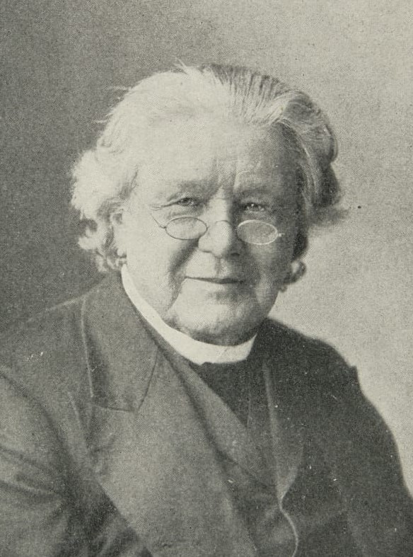 Portrait of man wearing glasses, suit, and clerical collar