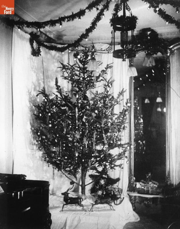Black-and-white photo of Christmas tree in a room decorated with garland and other Christmas decorations