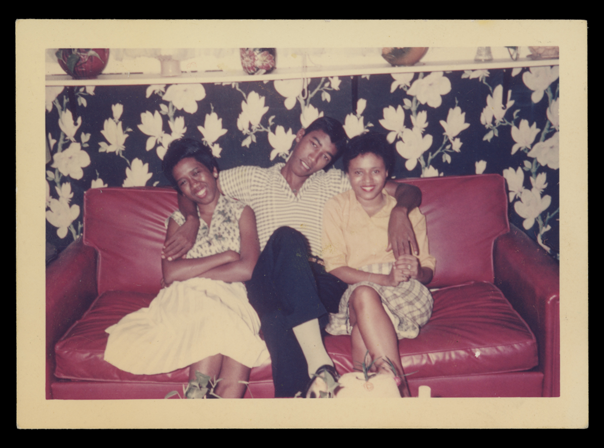 1960 photo of three people sitting on a couch in the Music Room. Behind, you can see a hint of the curtains.