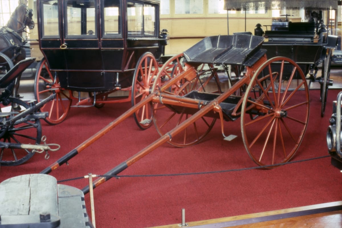 Breaking Cart, circa 1890 Simple open cart with two large wheels, in a room with other carriages