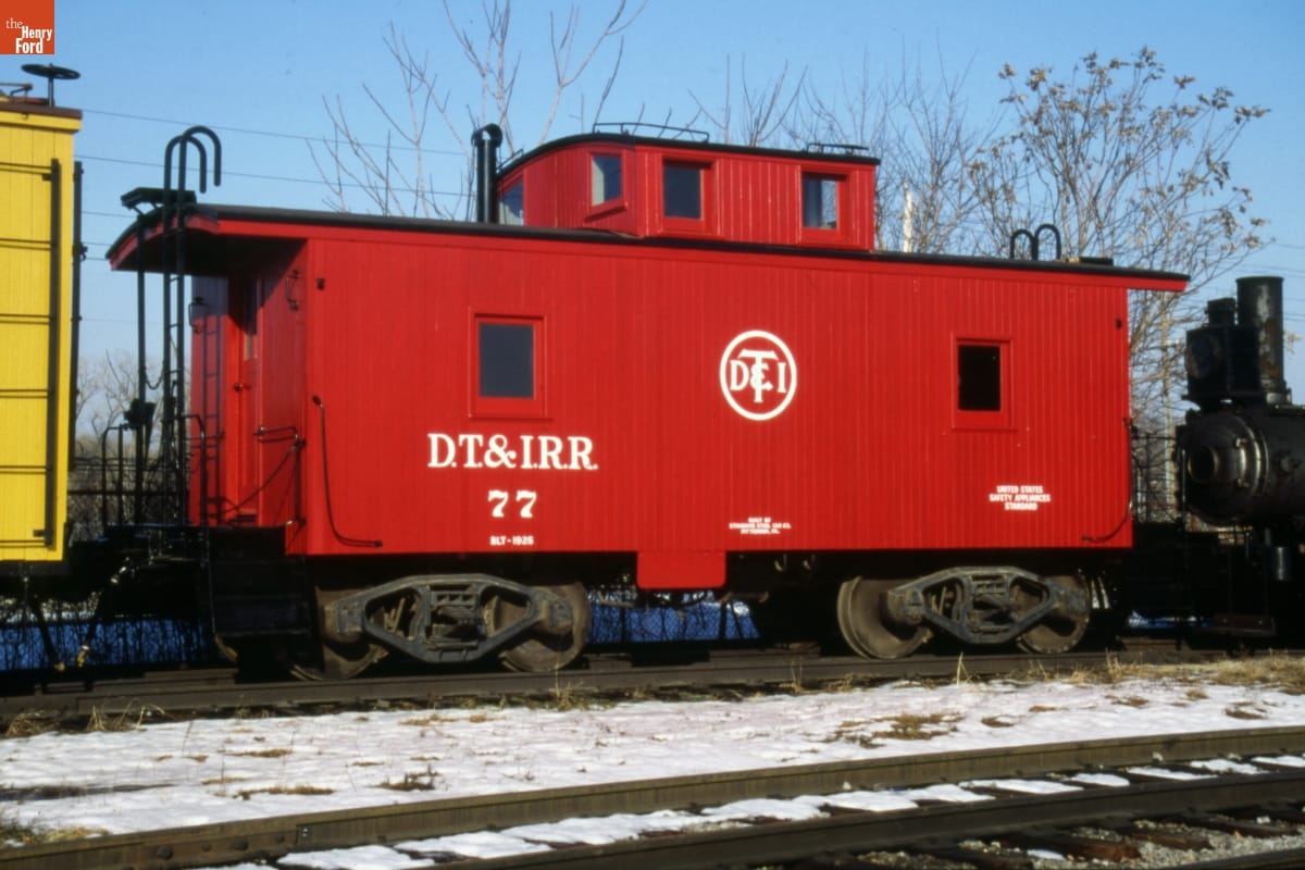 Red caboose with text on it sitting on railroad tracks