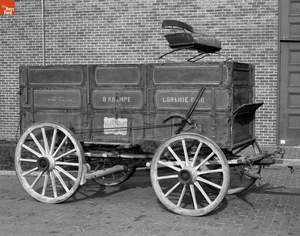 Boxy wooden wagon with text on side and driver's seat on top