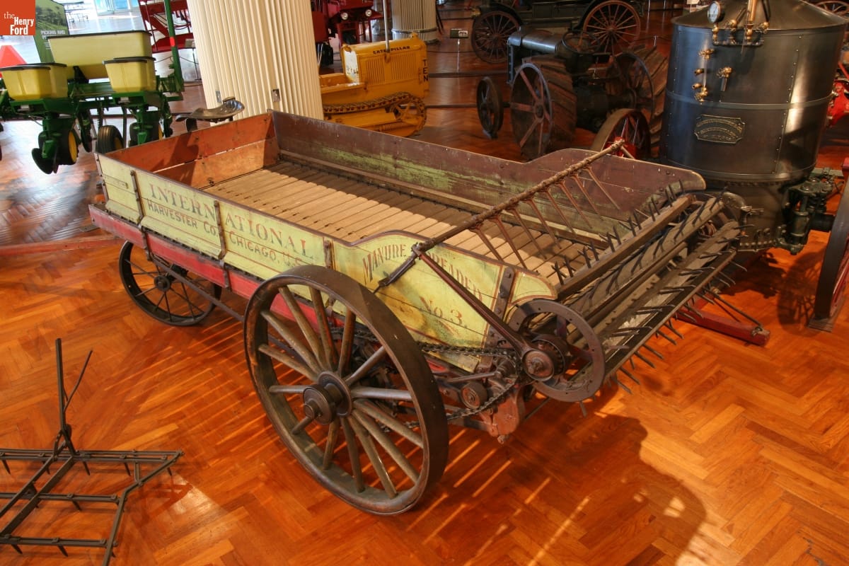 Yellow wooden cart with text on the side with a large wooden beater at one end