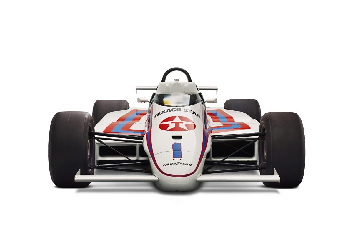 Head-on view of a low white race car with wide wheels