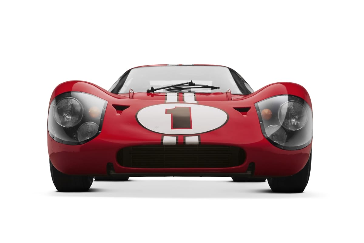 Head-on view of a low red race car with large number "1" in circle on hood