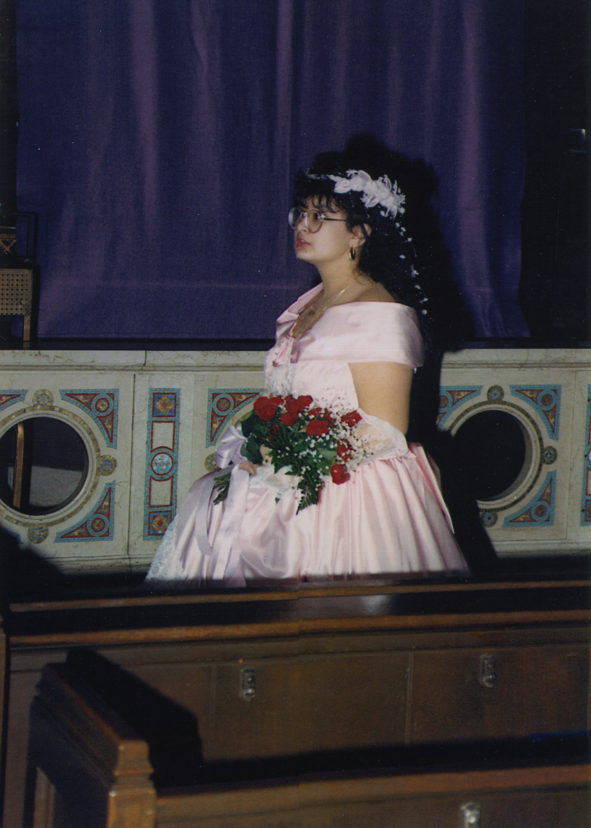 Profile of woman in pink dress holding a bouquet of roses in a formal building (church?)