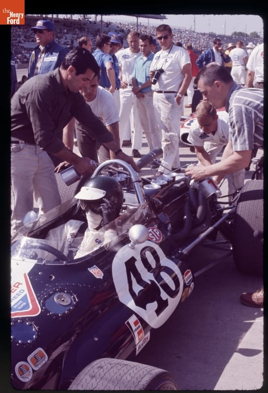 Eagle/Ford Race Car Driven by Jochen Rindt in the 51st Indianapolis 500, May 1967 Man sitting in race car with several people gathered around it; additional people in the middle distance and grandstands full of people in the far background