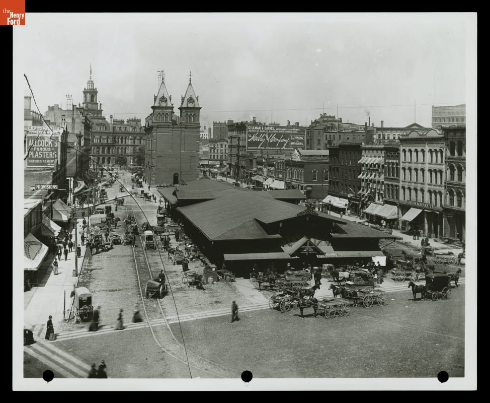 Central Market in Downtown Detroit, Michigan, circa 1890 City scene with large, low building in center of photo with people and horse carriages nearby