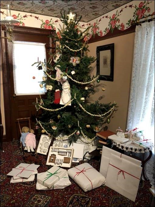 Decorated Christmas tree in corner of room with wrapped and unwrapped items underneath
